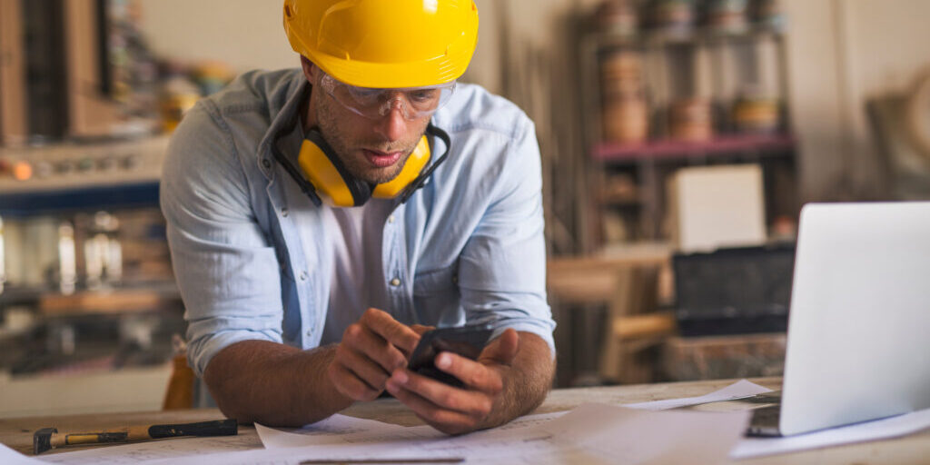 En arbetar som står med sin telefon