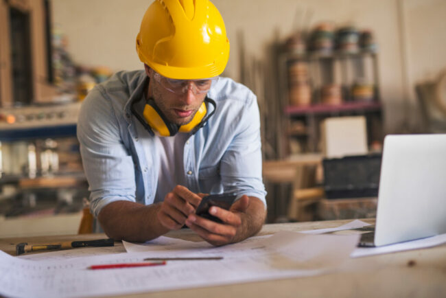 En arbetar som står med sin telefon